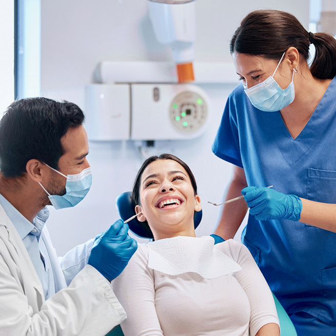 Smiling dental patient between two dentists