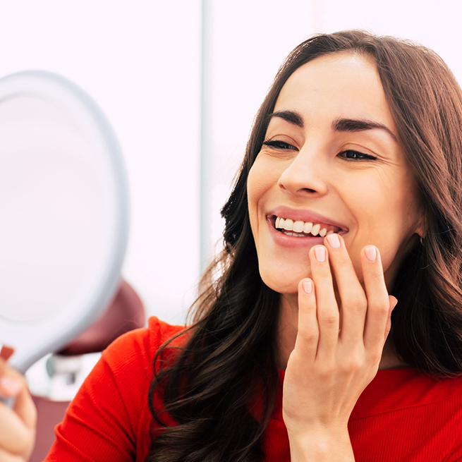 Woman with red shirt checking smile in mirror