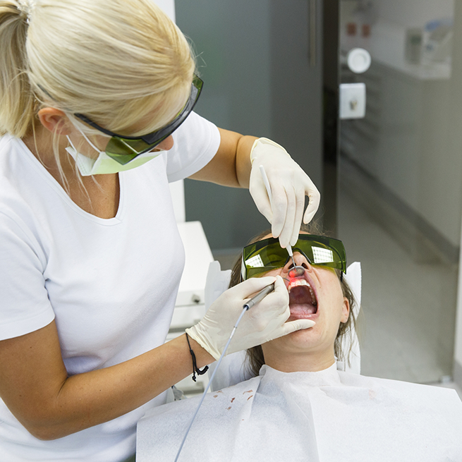 Dentist using soft-tissue laser to treat patient