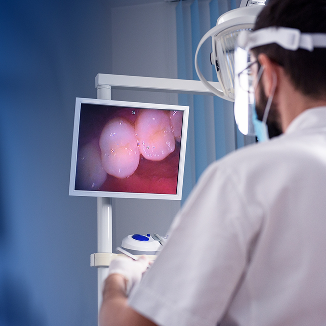 Male dentist looking at picture of teeth on monitor