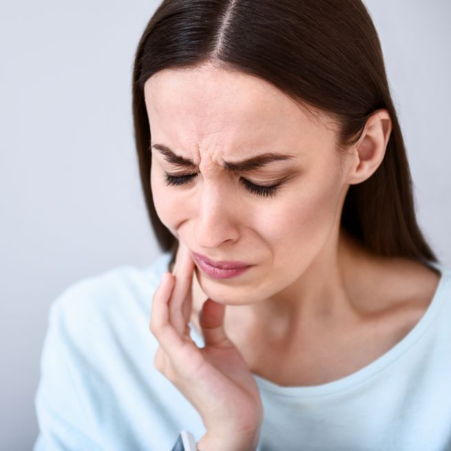 Close-up of woman with tooth pain needing emergency dentist