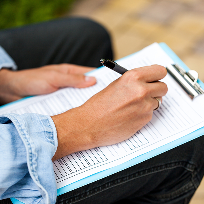 Close-up of woman filling out form on clipboard