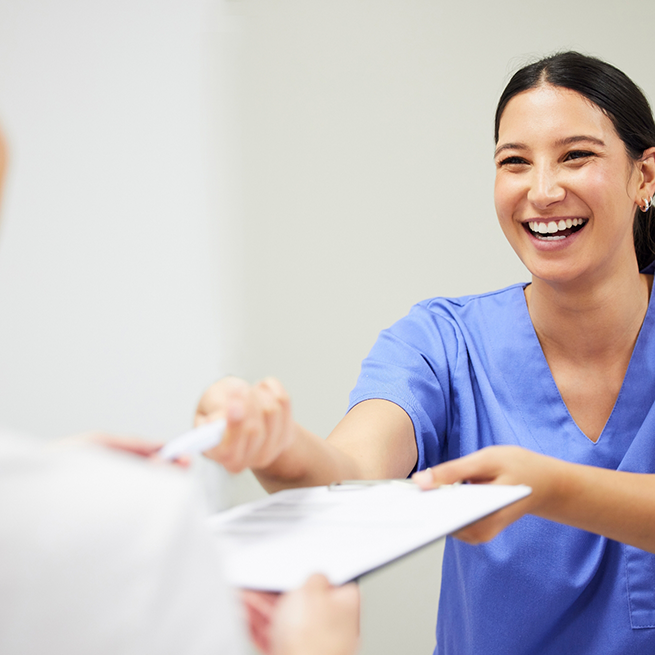 Dental team member handing clipboard to patient