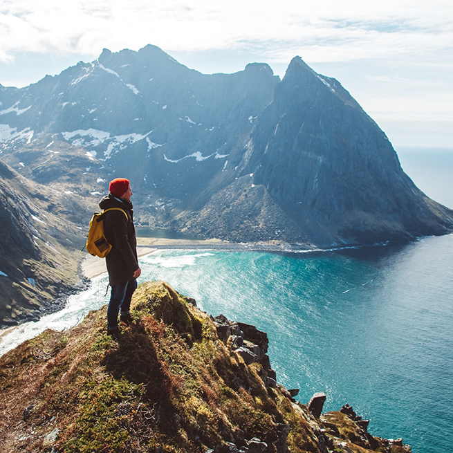 Man standing on ledge looking at ocean