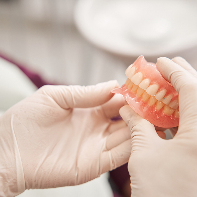 Close-up of gloved hands holding dentures