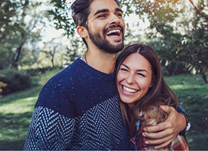 Man and woman smiling and hugging outside