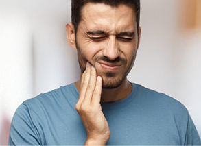 Bearded man touching his jaw and making pained expression