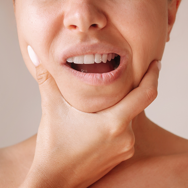 Close-up of woman with TMJ disorder in Bloomfield rubbing jaw